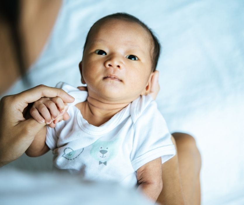 parent holding baby looking at camera