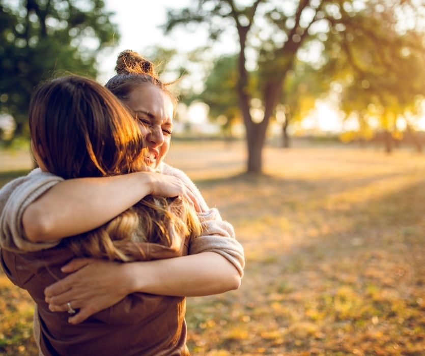 woman hugging her friend who told her she's pregnant