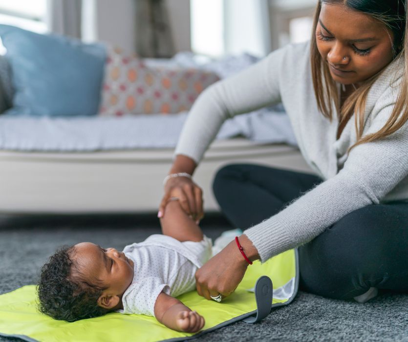 mom cloth diapering baby on change mat