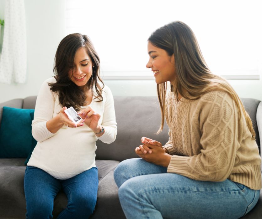 pregnant woman showing a sonogram photo to her doula