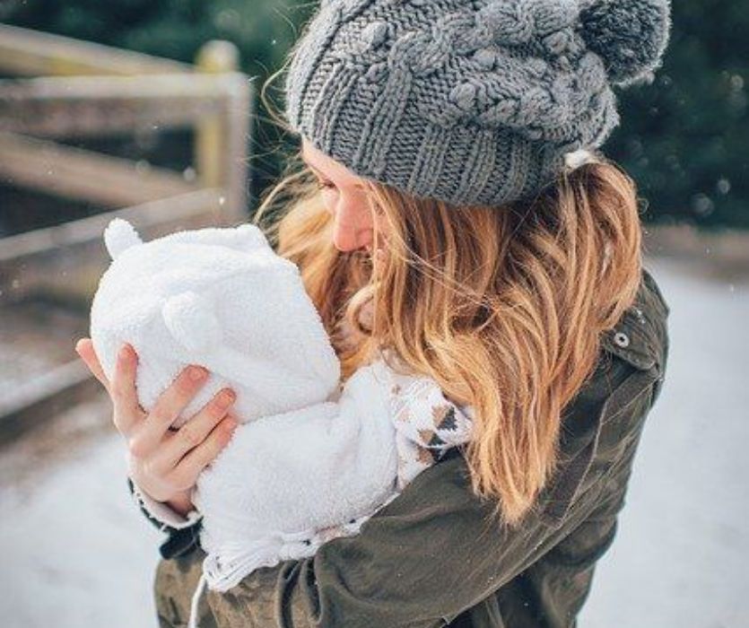 Mom holding baby in snowsuit - best winter gear for baby