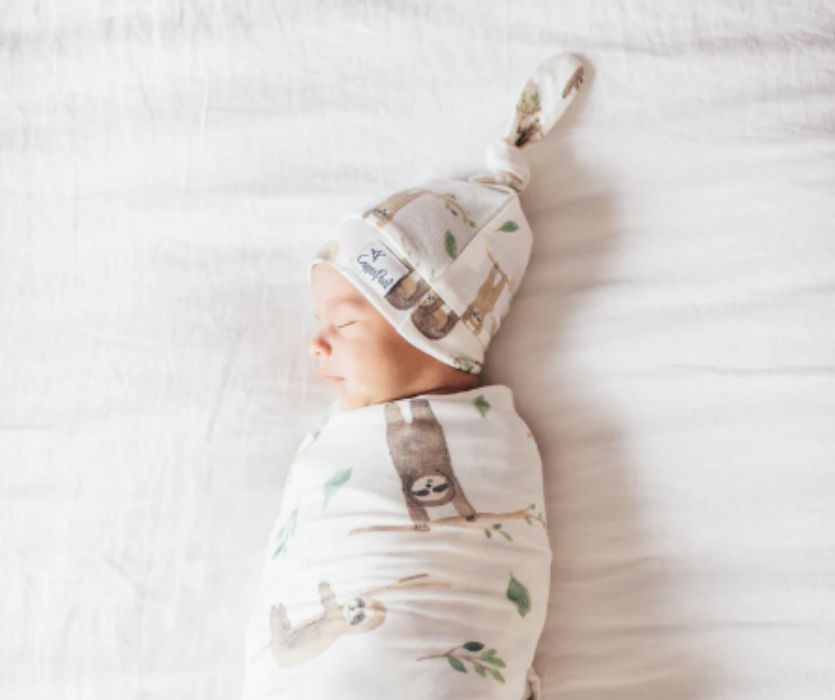 baby wearing sloth swaddle and sloth top knot hat
