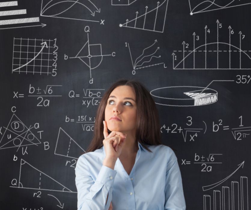 woman standing in front of chalkboard with calculations on it