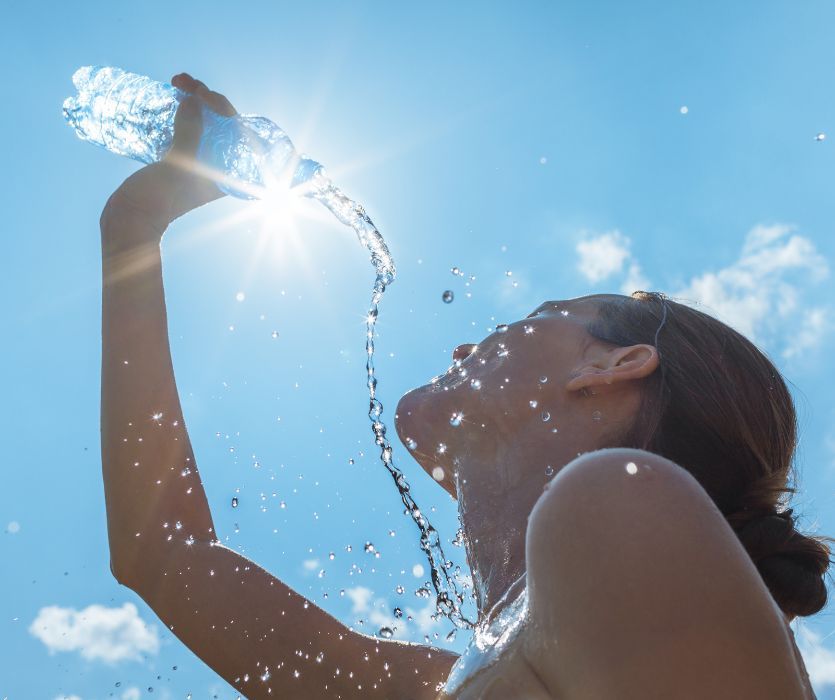 pregnant woman pouring a bottle of water on herself on a hot day