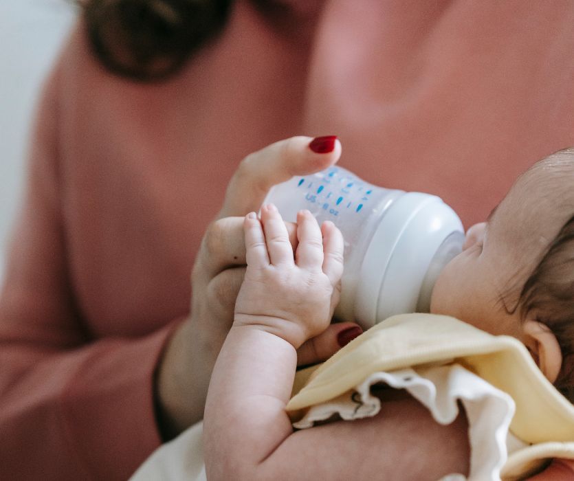 mom feeding her baby formula with a baby bottle