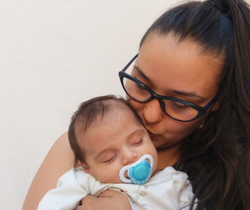 young mother kissing her newborn baby