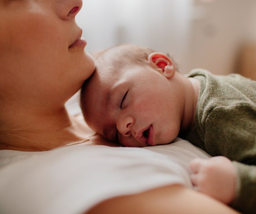 mom suffering from postpartum depression holding her sleeping baby