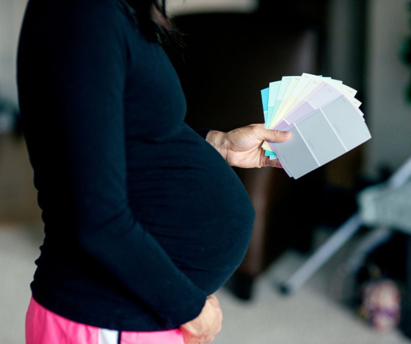 pregnant woman holding paint chips to paint a nursery