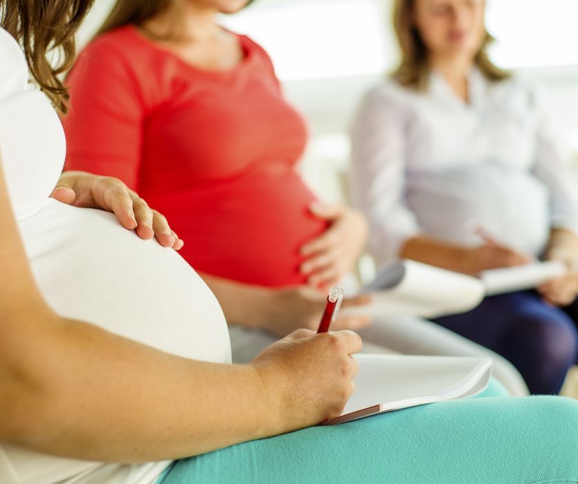 three pregnant women in a birthing class taking notes