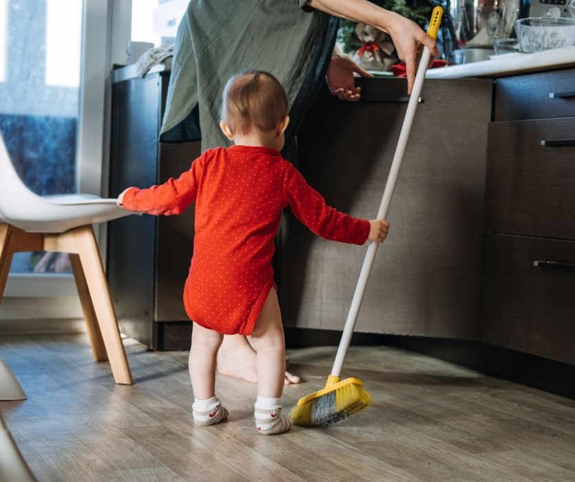 mom sweeping floor with baby helping