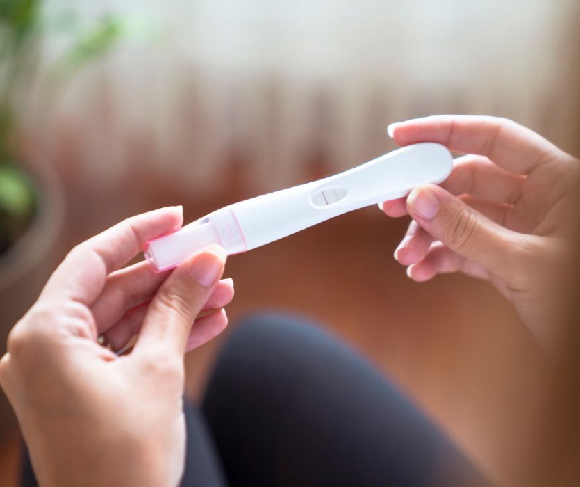 woman TTC holding pregnancy test with faint positive line