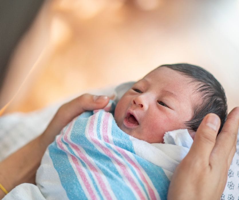newborn baby wrapped in a hospital blanket