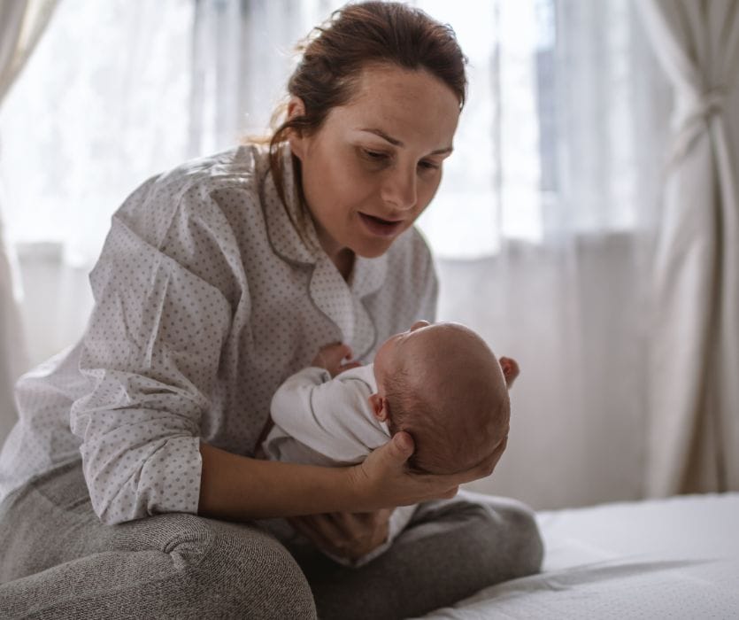 new mom holding baby while struggling with postpartum anxiety