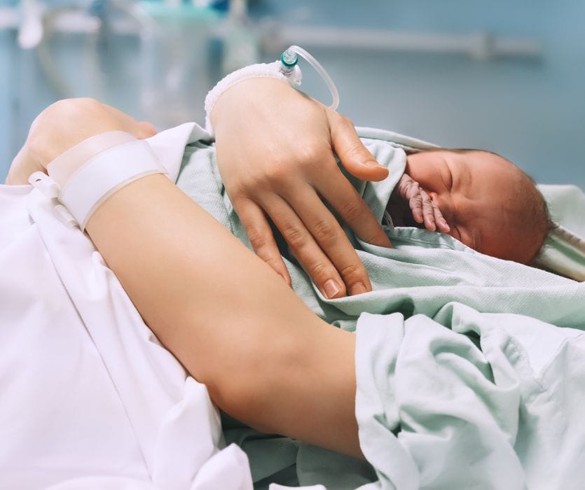 woman holding her newborn baby after giving birth