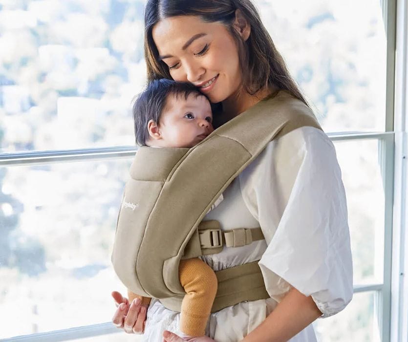 mom holding her newborn in a baby carrier