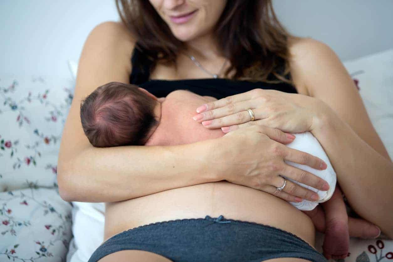 postpartum woman holding newborn after giving birth