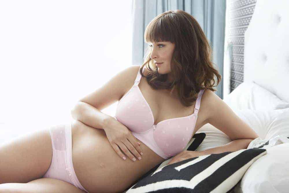pregnant woman sitting on the bed in a maternity underwear