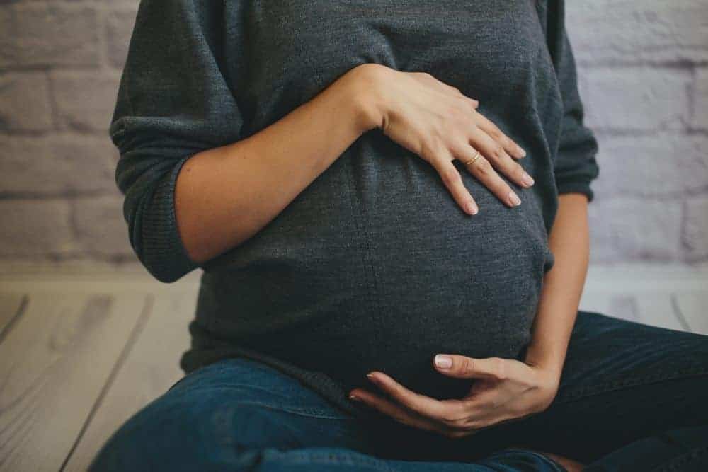 pregnant woman holding her belly experiencing third trimester symptoms