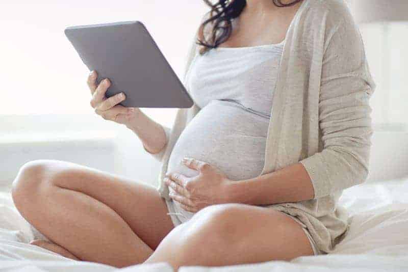pregnant woman on iPad looking up The Best Gear When You're Pregnant and On Bed Rest