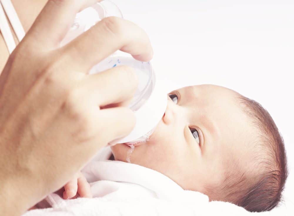 parent feeding a newborn with formula feeding gear