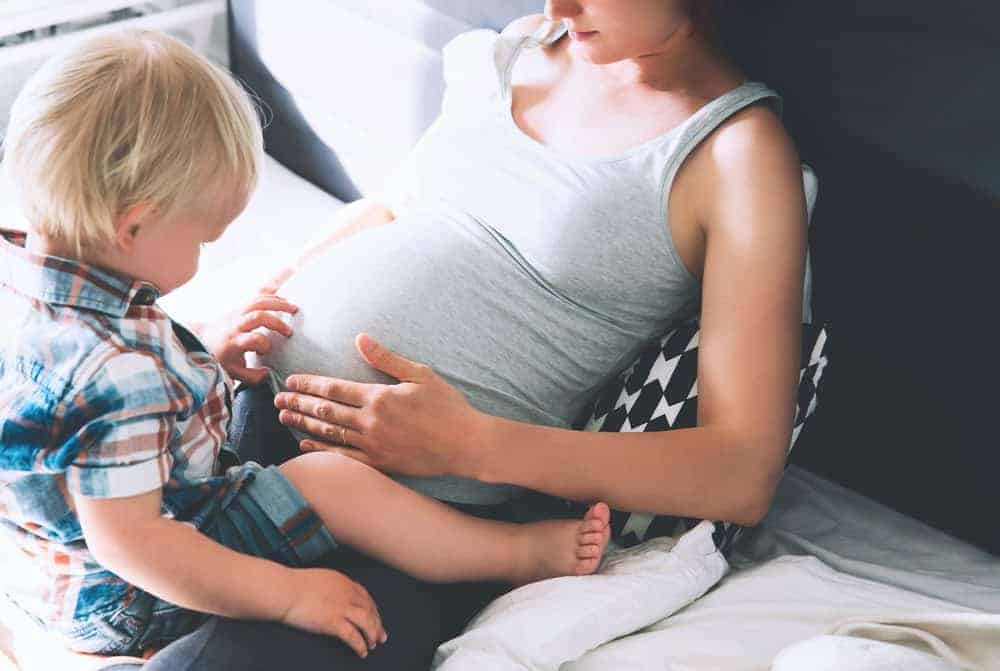 baby and mom sitting in bed sharing sweet moment during last pregnancy