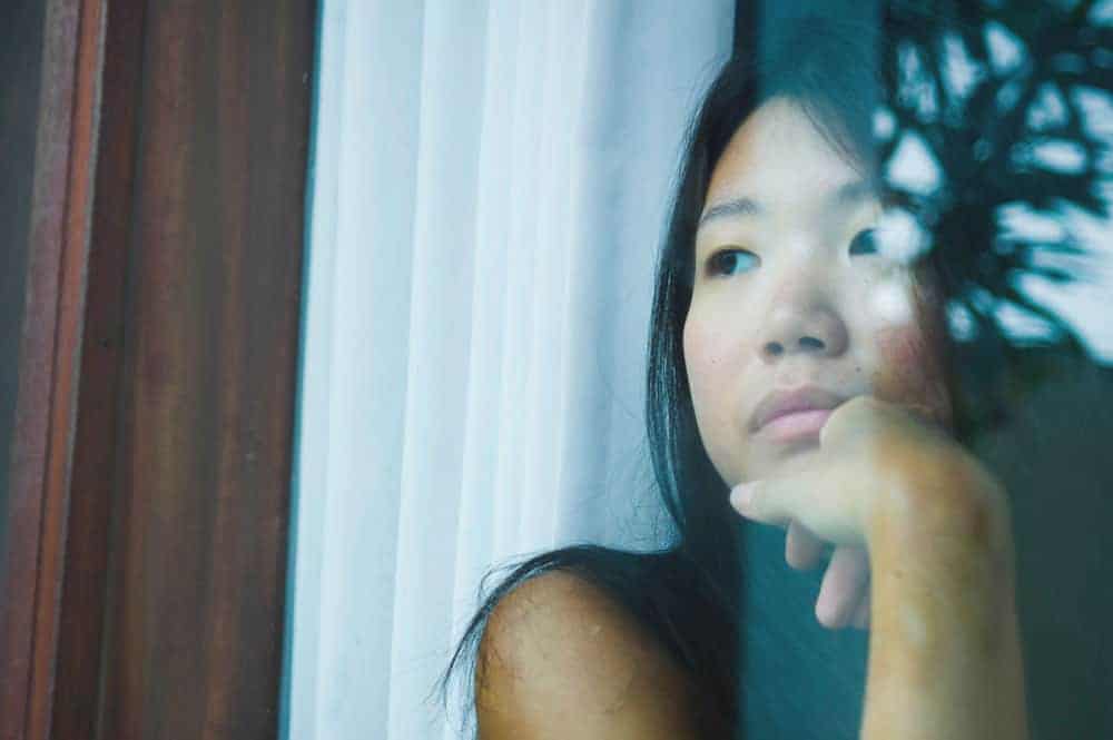 woman looking out the window after a miscarriage