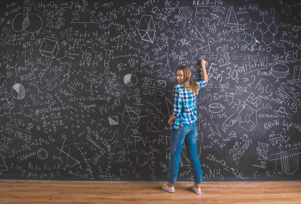 woman writing out complicated equations on a very large chalkboard.