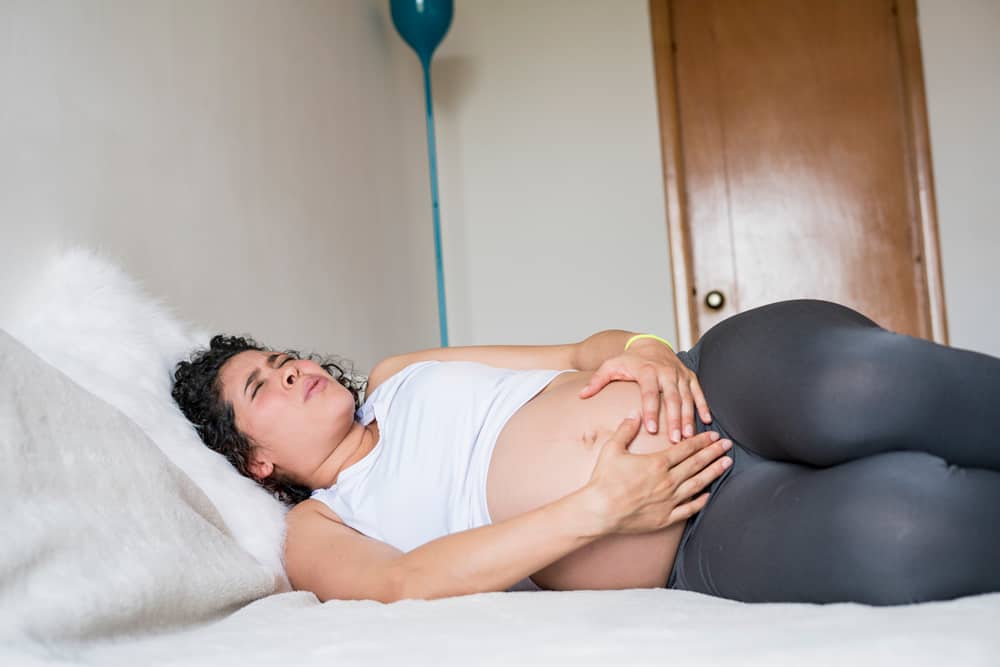 pregnant woman lying on bed suffering from pubis diastasis
