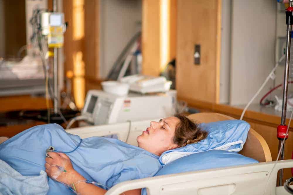 woman laying down in a hospital bed in labor in lithotomy position