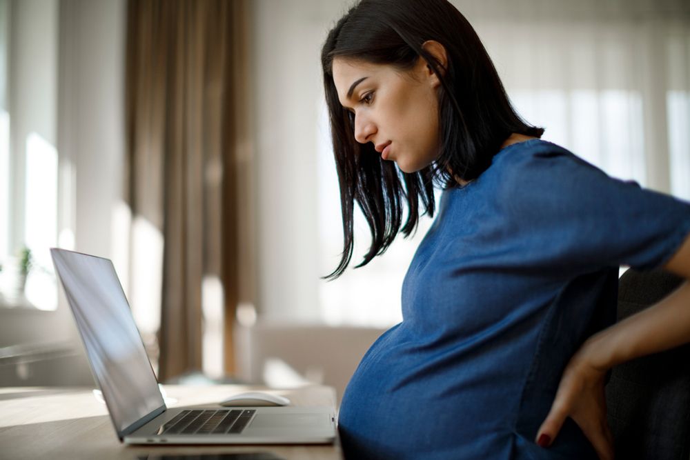 pregnant woman on laptop worried about pregnancy symptom
